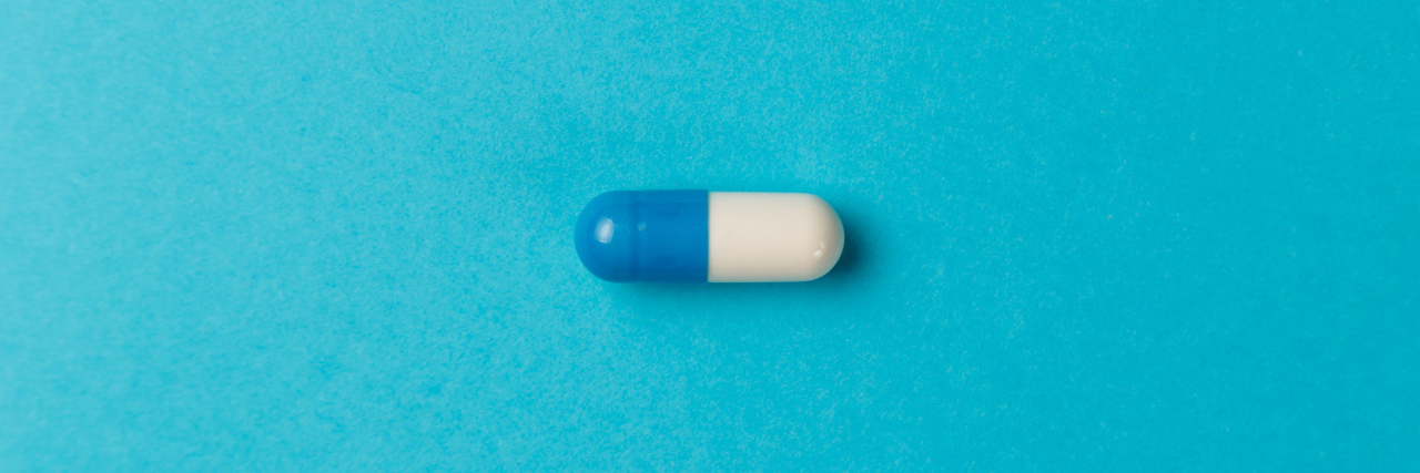 Small Study Suggests Antidepressant Fluvoxamine Could Treat COVID-19 Medication capsule on blue background
