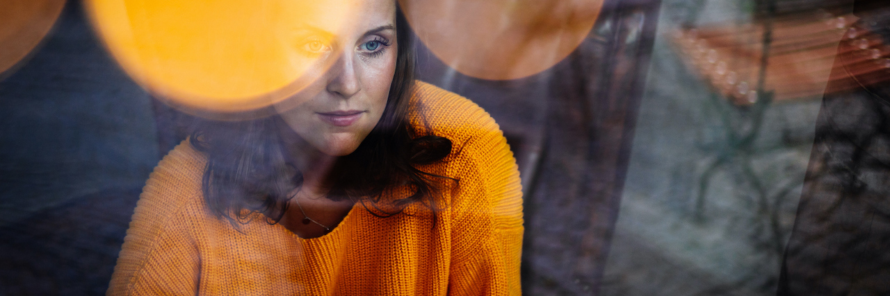 What Someone With Schizoaffective Disorder Thinks About Suicide Young woman sitting thoughtfully in a leather armchair behind a window.