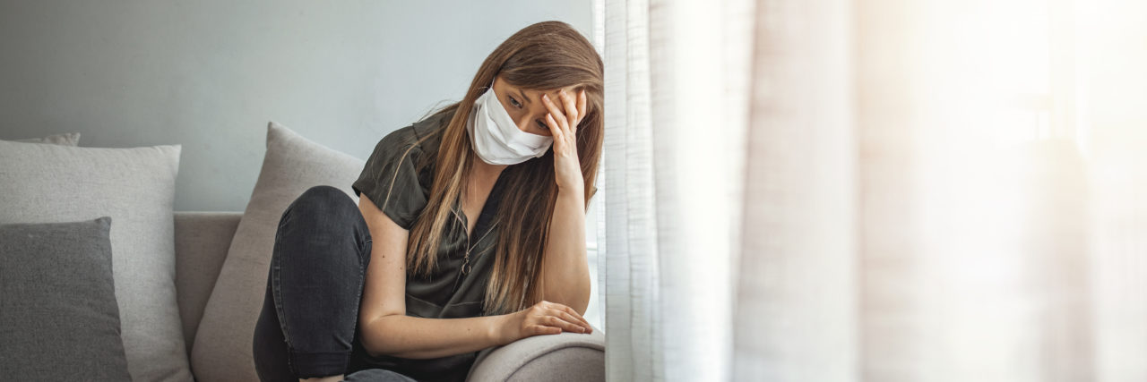 Researcher Identifies 16 COVID-19 Personality Types Woman sitting on a coach wearing a mask