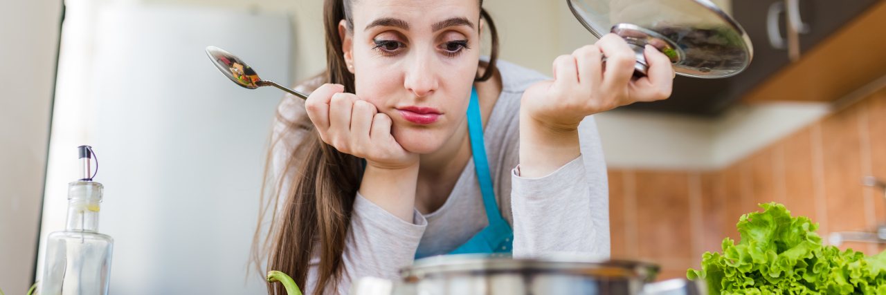 Unhappy woman looking at pot in kitchen.