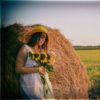 Woman with sunflowers and haystack.