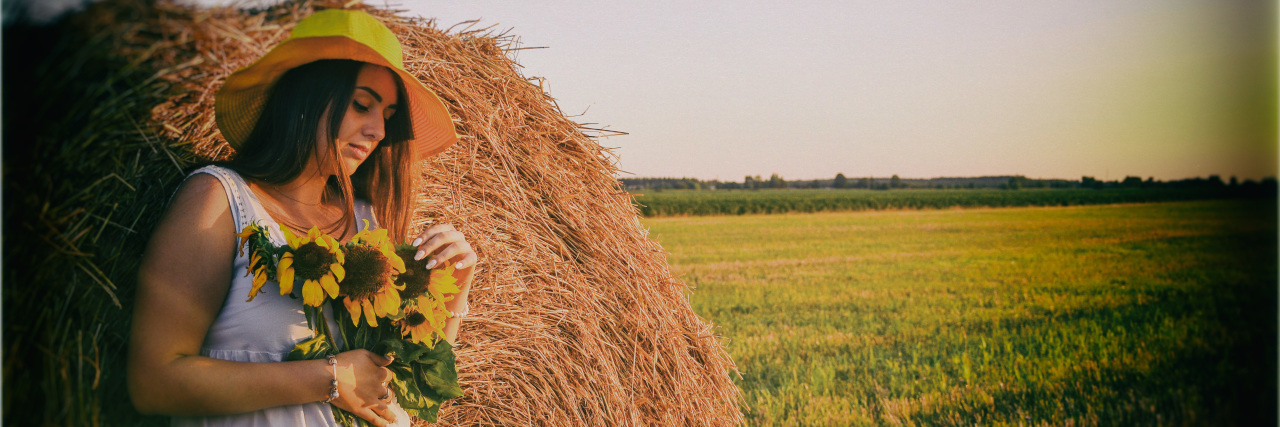 What Epilepsy Taught Me About Coping With the COVID-19 Pandemic Woman with sunflowers and haystack.