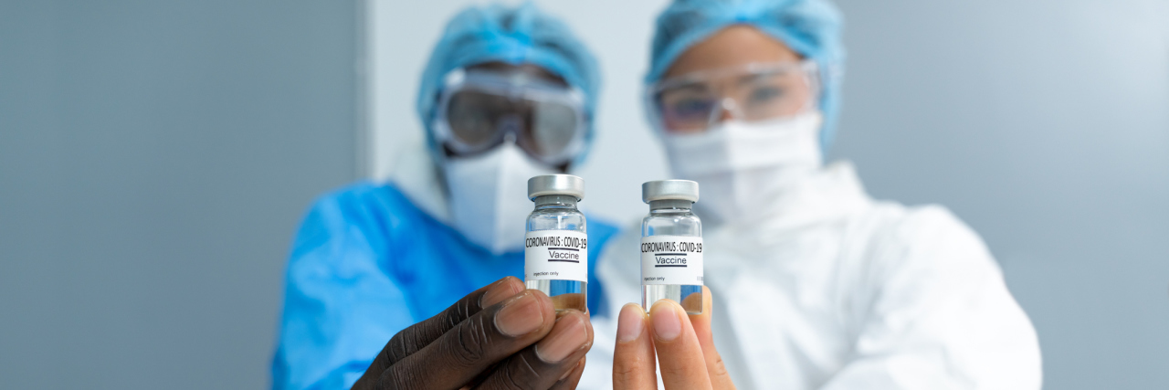 scientists in laboratory holding vial of coronavirus vaccine.
