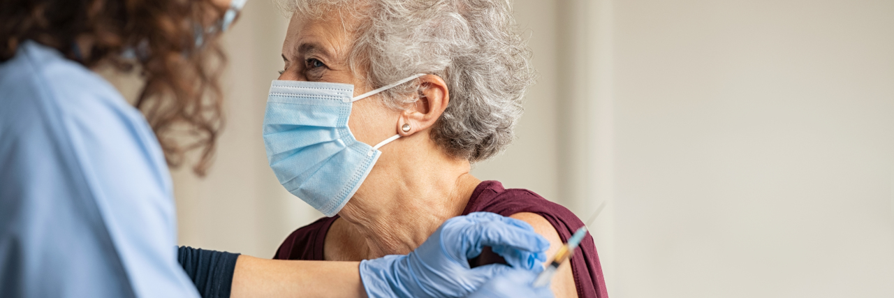 Doctor giving Covid vaccine to senior woman.