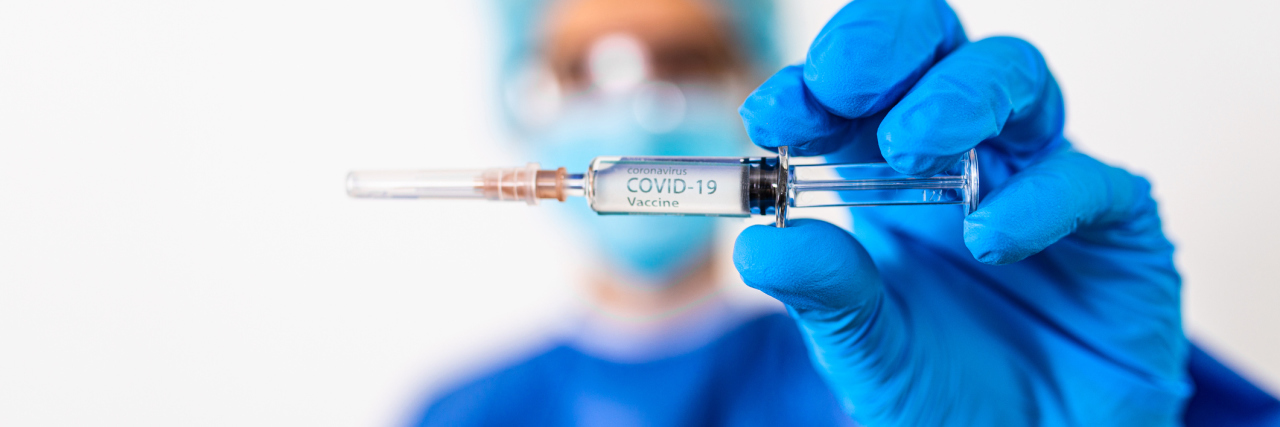 Infectious doctor shows COVID 19 vaccine in a loaded injection needle