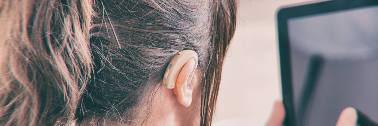 Should I Disclose That I'm Hard of Hearing on My Resume? Woman with hearing aid using tablet.