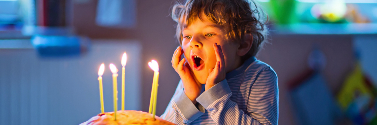 Child about to blow out five candles on his birthday cake