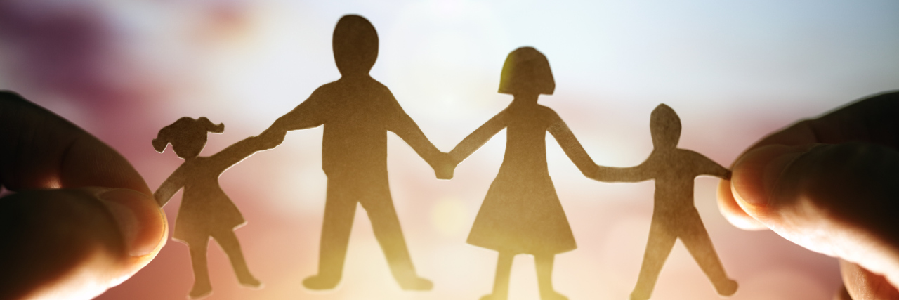 Why I'm Not Hiding My Family's Struggle With Mental Illness Anymore paper chain of a family held up to the sunset