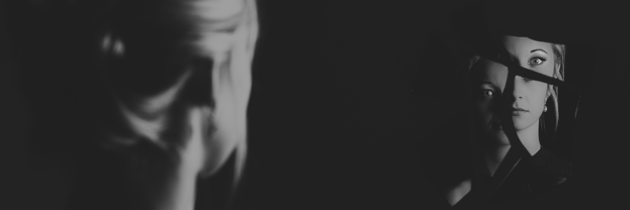Borderline Personality Disorder ‘Mirroring’ Means I Don’t Know Who I Really Am black and white photo of a woman looking into her reflection in a broken mirror