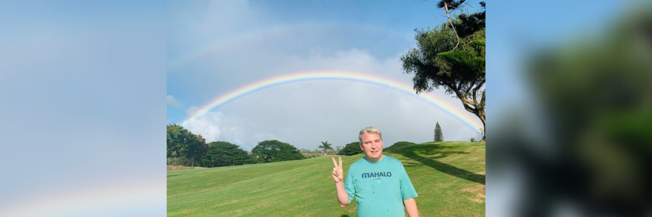 How 'Aloha' Helps My Bipolar Disorder and Life After Addiction photo of the contributor Conor Bezane in Hawaii, making a peace sign with his hand, posing underneath a double rainbow
