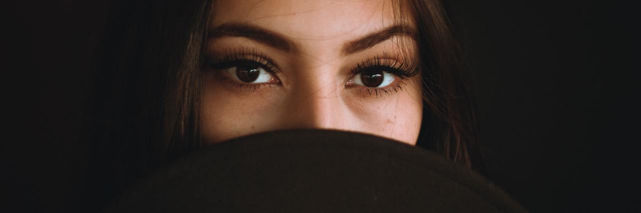My Trauma Truth as a Survivor and Student of James Franco photo of latine woman looking into camera with serious expression and covering her mouth with a hat