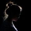 photo of a woman silhouetted in darkness, only the edge of her face and hair in profile can be seen