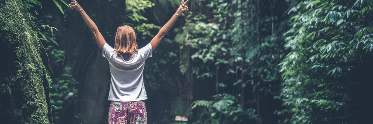 Forgetting to Have Fun When You Live With Depression photo of woman in forest with her arms raised in happiness
