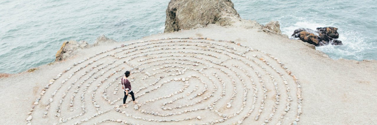 Photo of woman walking in a rock maze by the sea