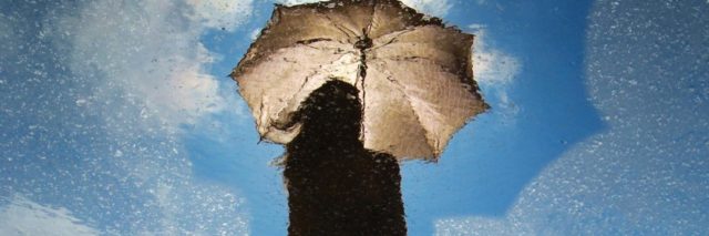 Woman holding an umbrella against a rainy but blue sky