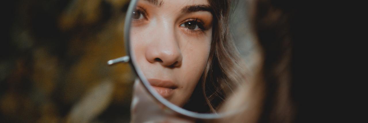 photo of woman looking into mirror reflection, focused on her reflection