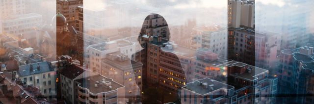 photo of a woman's reflection on a window overlooking a city, from a skyscraper