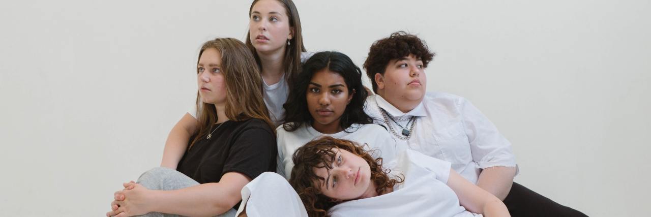 Why So Many Millennials Have Anxiety group of Millennial women of different ethnicities, sitting on the floor with each other looking tired or depressed