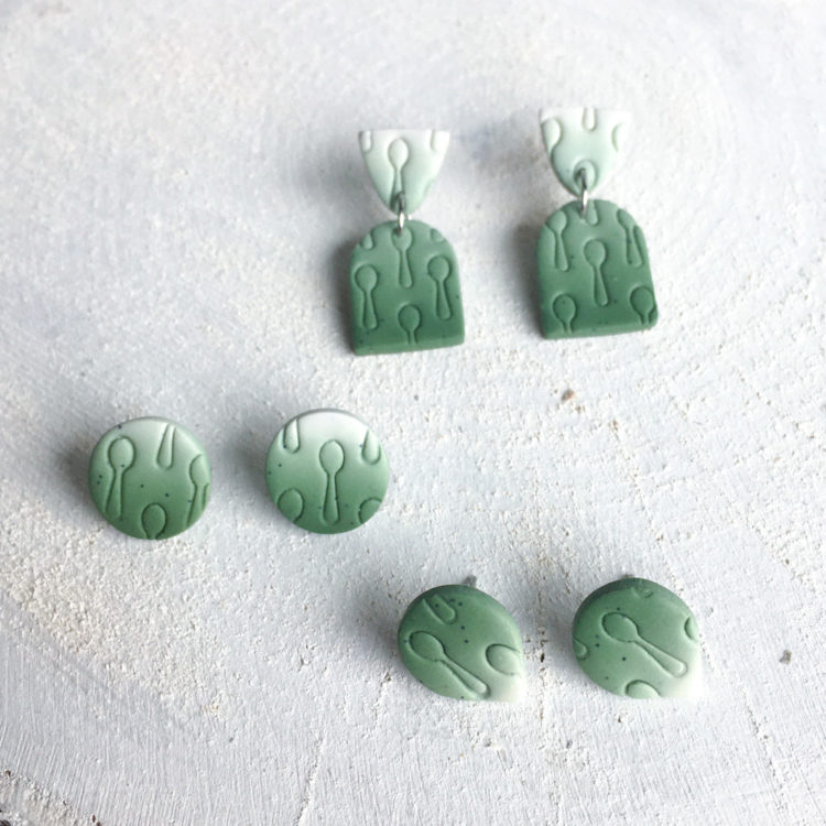 Three sets of green earrings with a spoon pattern on a white background