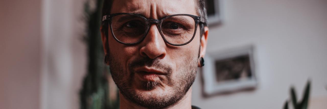 Being Analytical Helps Separate Schizophrenia Delusions From Reality A young white man in glasses with short brown hair making a confused face