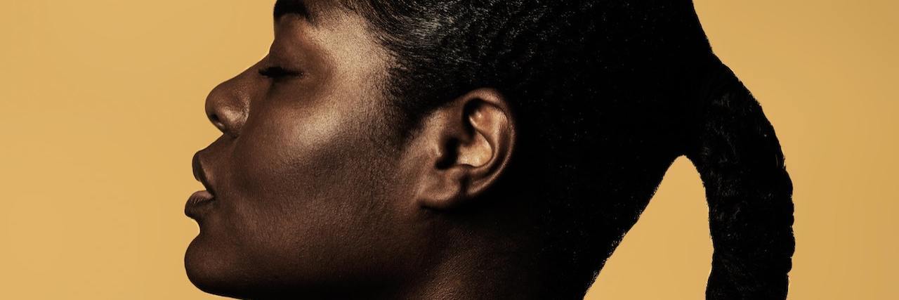 a Black woman, profile, against a yellow background.