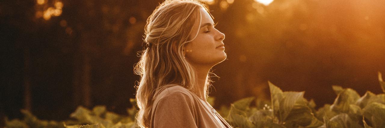2020, COVID-19 and Politics: Lessons Learned as a Trauma Survivor photo of a woman standing in a field at sunset, head raised and eyes closed