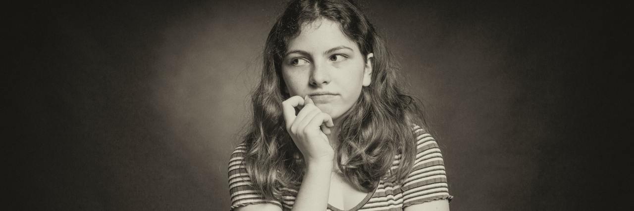 Don't Tell Someone With Depression They're Bringing You Down sepia tone photo of woman looking uncaring, with a slight smile, her hand raised to her chin and looking off-camera