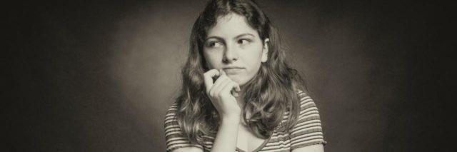 sepia tone photo of woman looking uncaring, with a slight smile, her hand raised to her chin and looking off-camera