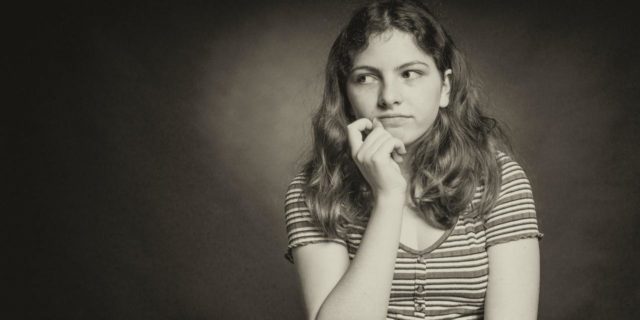 sepia tone photo of woman looking uncaring, with a slight smile, her hand raised to her chin and looking off-camera