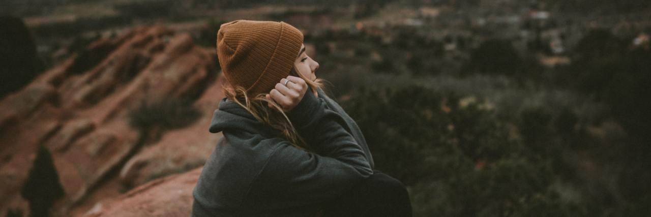 If My PTSD Could Talk, This is What It Would Say photo of a woman sitting on a rock in the desert at sunset