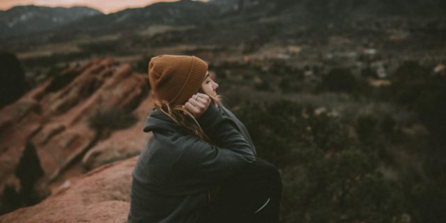 photo of a woman sitting on a rock in the desert at sunset