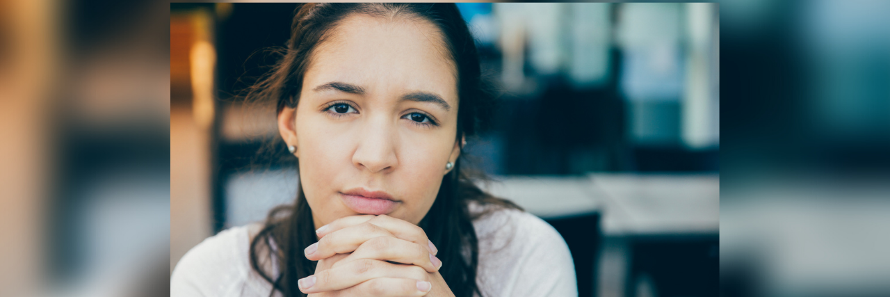 Be Kind and Listen to Those With Borderline Personality Disorder Woman holding her hands clasped and looking straight at camera