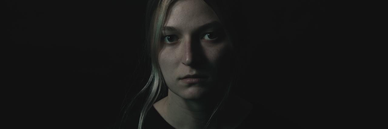 Read This if You Feel Emotionally Overwhelmed With COVID-19 dark photo of a woman looking upset into camera