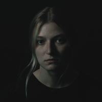 dark photo of a woman looking upset into camera