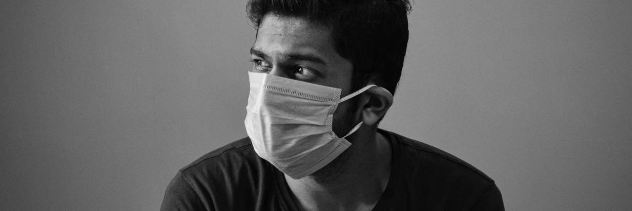 black and white photo of man wearing a face mask looking away from camera
