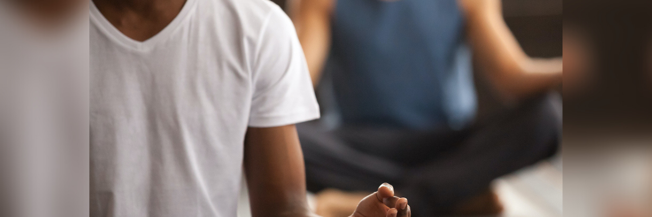 How Buddhist Teachings About Suffering Can Help Manage Anxiety Image of Black man and White man sitting in meditative pose