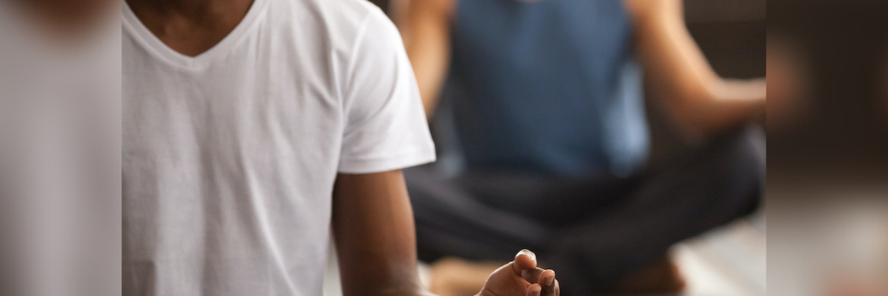 Image of Black man and White man sitting in meditative pose