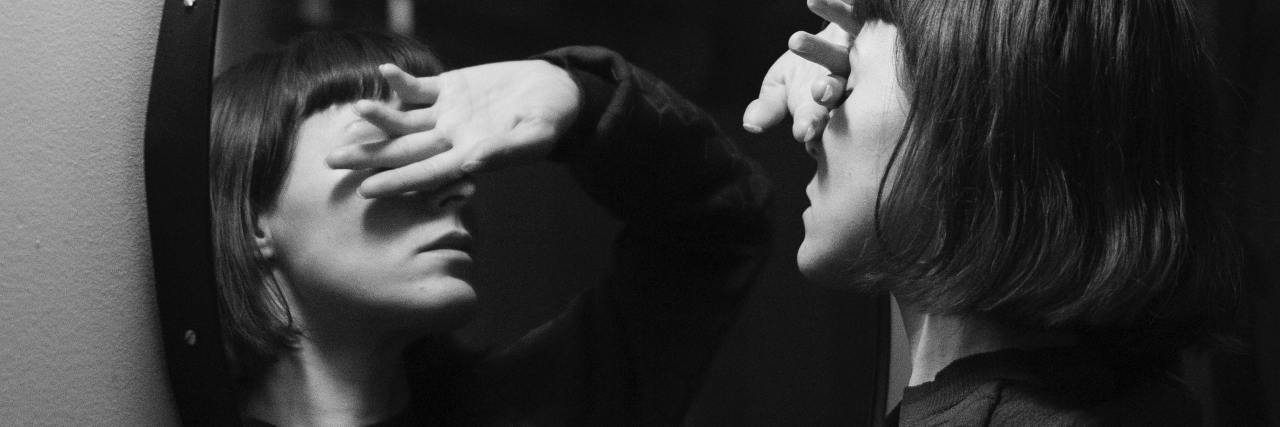Proven Ways to Handle Your Internal Bully black and white photo of a woman leaning against a mirror with her eyes covered with her hand