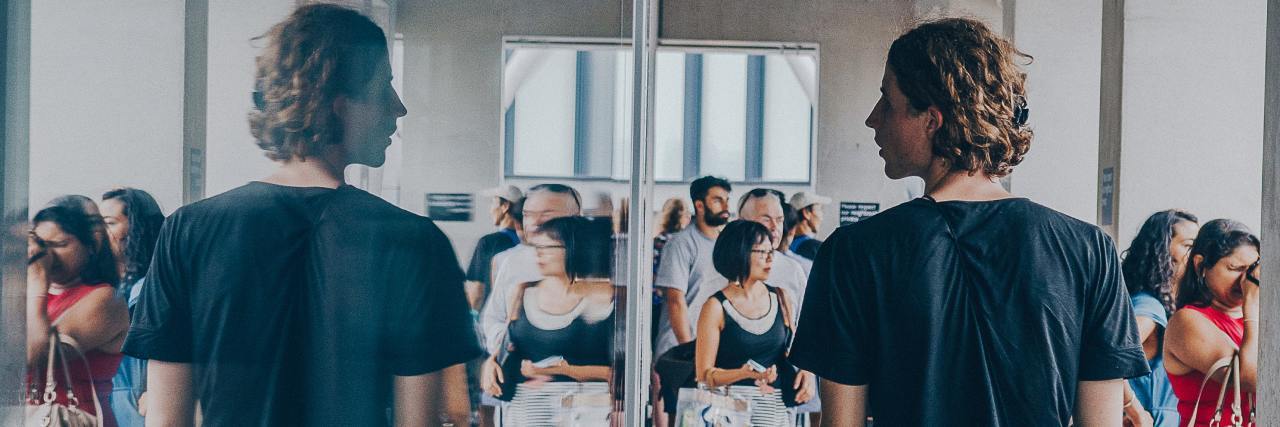 Practicing Honesty With Yourself Can Help Your Mental Health photo of man walking along a street with a long mirror, looking at his reflection with others reflected too