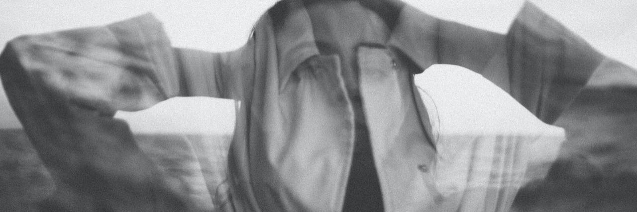 Black and white blurry portrait of a woman holding her jacket over her head