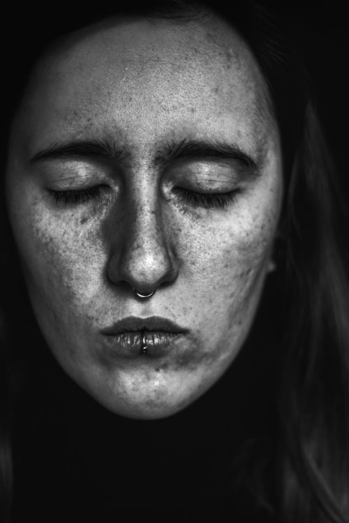 black and white photo of a white woman's face with eyes closed, lips pursed 