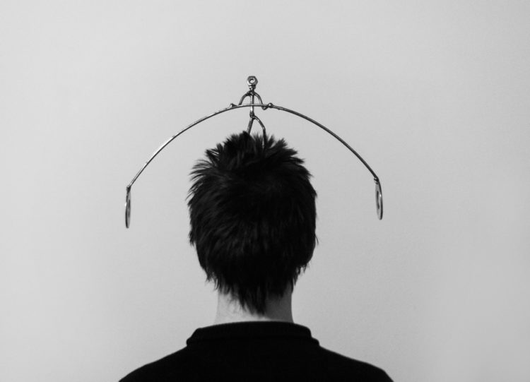 black and white photo of the back of someone with short, spunky hair and a metal rod over the head