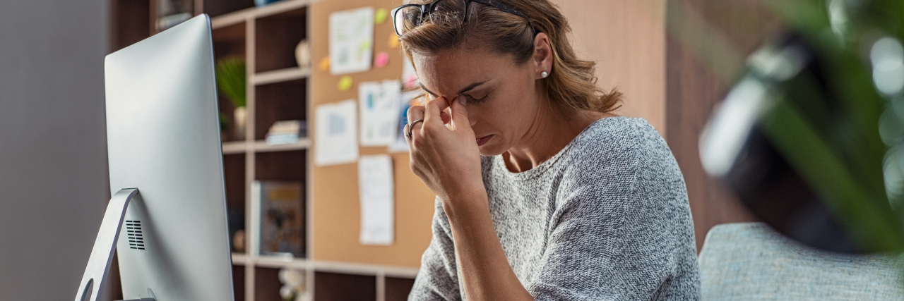 Experiencing Hypomania and Exhaustion With Bipolar Disorder photo of a woman sitting at a computer looking exhausted