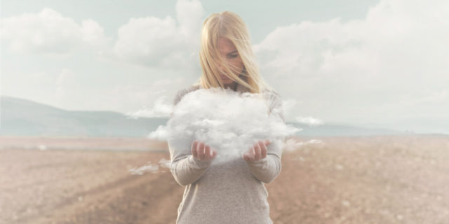 digitally edited photo of a woman holding a cloud in a field