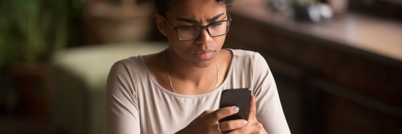 COVID-19 Revealed Society's Disregard of People With Chronic Illness Woman looking at her phone screen with dismay.