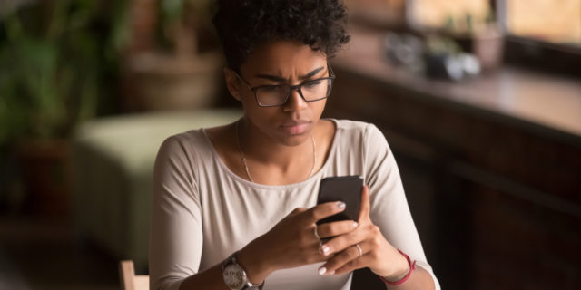 COVID-19 Revealed What Many Americans Really Think About People With Chronic Illness Woman looking at her phone screen with dismay.