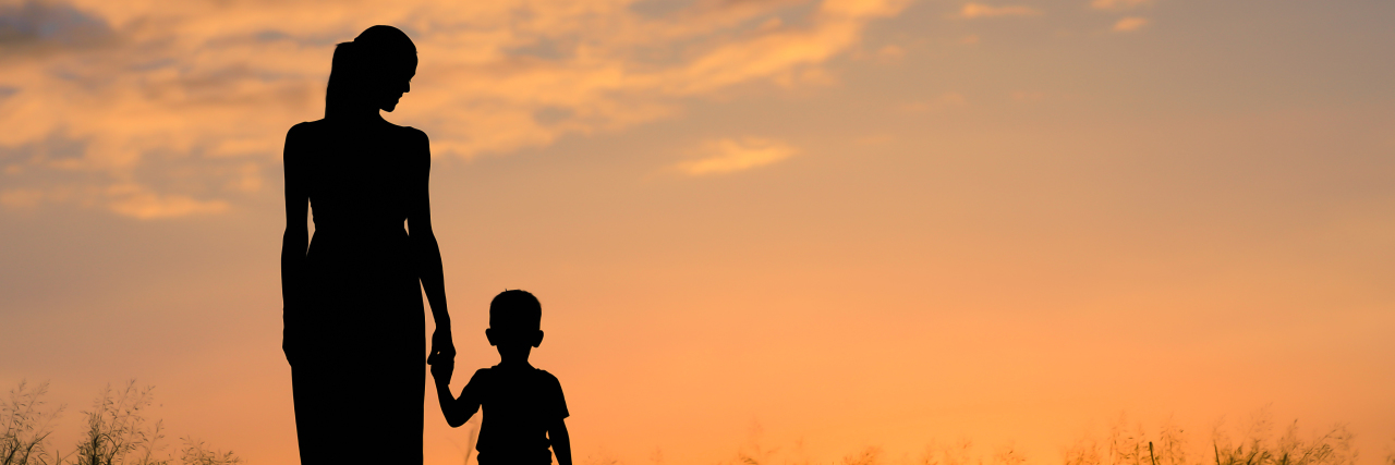 Parents of Autistic Children Need to Listen to Autistic Adults Mother and child silhouette walking in a field at sunset.