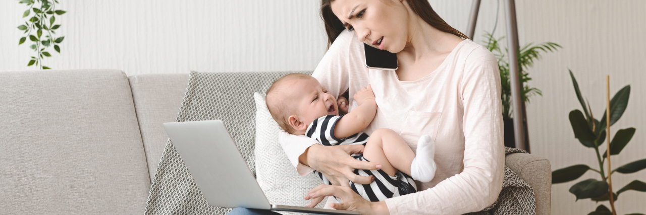 Mother holding crying baby and calling doctor.