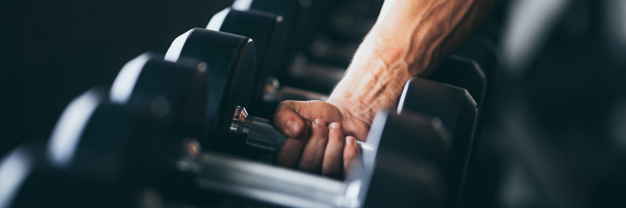 Rows of dumbbells with someone's hand holding onto one