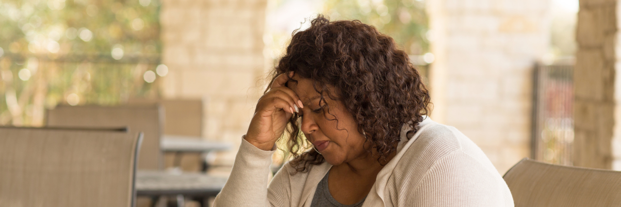 Going Through Perimenopause With Fibromyalgia Middle aged woman in deep thought.